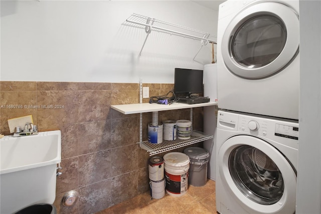 washroom featuring tile walls, stacked washer and dryer, and tile patterned floors