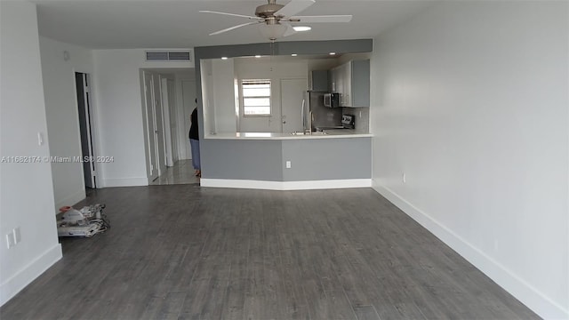 unfurnished living room featuring dark wood-type flooring and ceiling fan