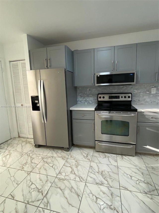 kitchen featuring appliances with stainless steel finishes, gray cabinetry, and tasteful backsplash