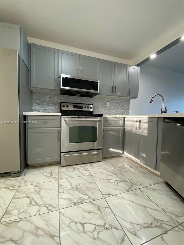 kitchen featuring appliances with stainless steel finishes, tasteful backsplash, ventilation hood, and gray cabinetry