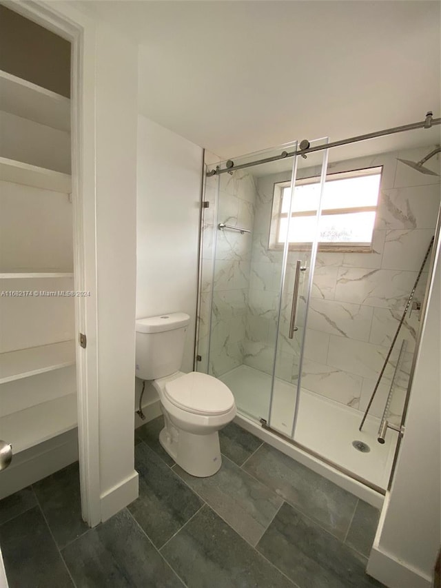 bathroom with toilet, tile patterned floors, and a shower with shower door