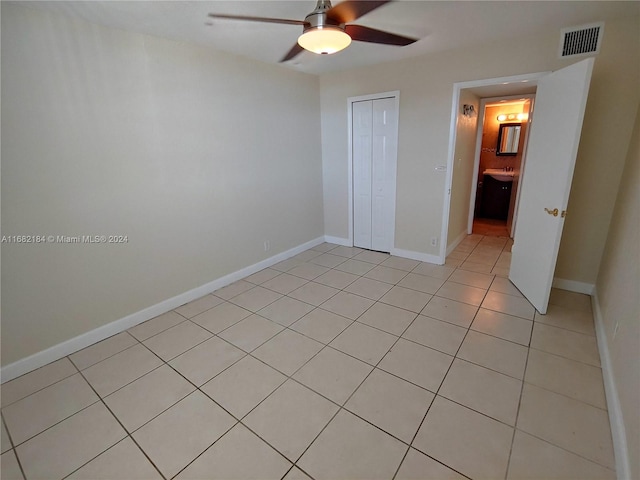 unfurnished bedroom with a closet, light tile patterned floors, and ceiling fan