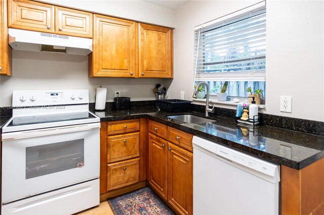 kitchen with white appliances, dark stone countertops, and sink