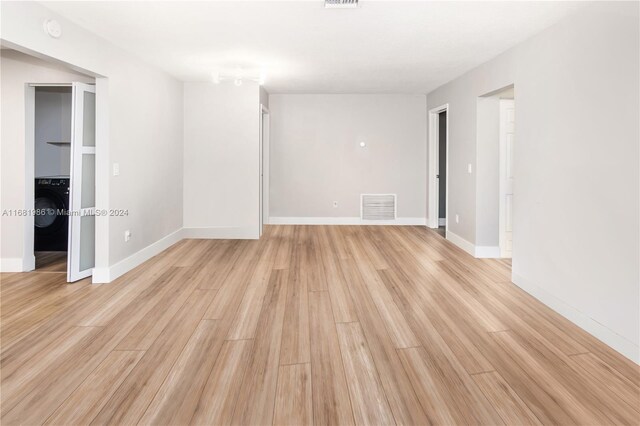 empty room featuring washer / dryer and light wood-type flooring