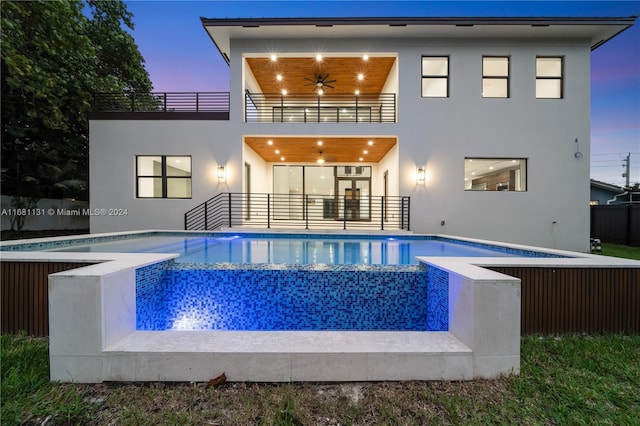 back house at dusk with a fenced in pool, ceiling fan, a balcony, and french doors