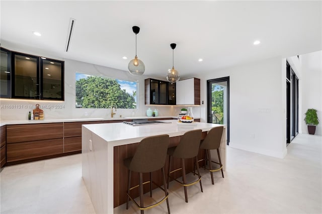 kitchen with pendant lighting, a center island, a kitchen breakfast bar, sink, and stainless steel gas cooktop