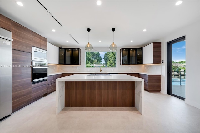 kitchen featuring built in appliances, a large island, hanging light fixtures, and a wealth of natural light