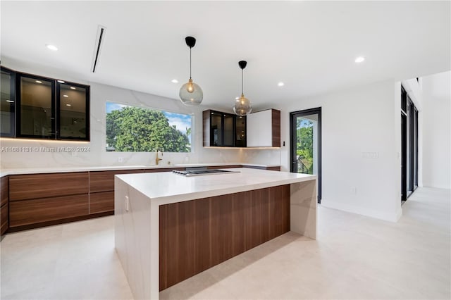 kitchen featuring pendant lighting, stainless steel gas cooktop, a spacious island, and sink