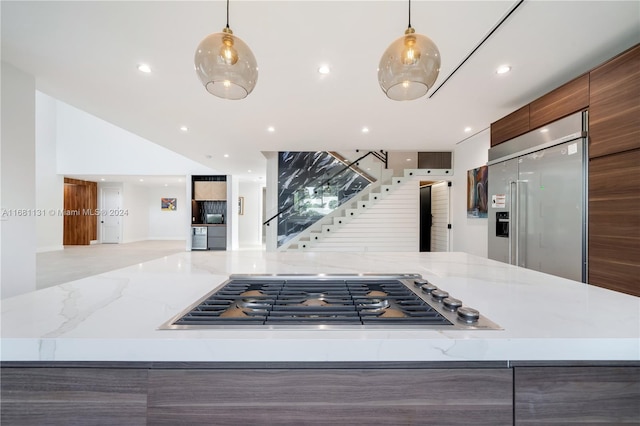 kitchen featuring stainless steel appliances, light stone counters, and hanging light fixtures