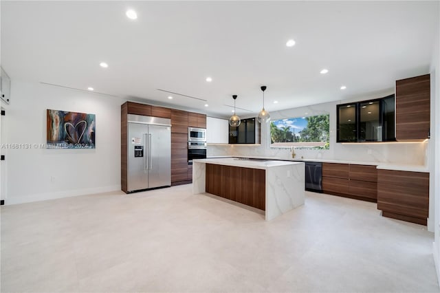 kitchen featuring a center island, sink, built in appliances, decorative backsplash, and decorative light fixtures