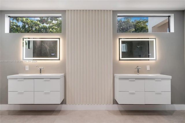 bathroom with concrete flooring, vanity, and a healthy amount of sunlight