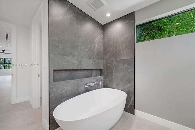 bathroom featuring a tub to relax in, concrete floors, and tile walls