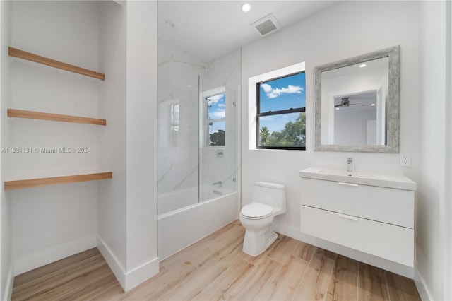 full bathroom featuring vanity, tiled shower / bath, hardwood / wood-style flooring, ceiling fan, and toilet