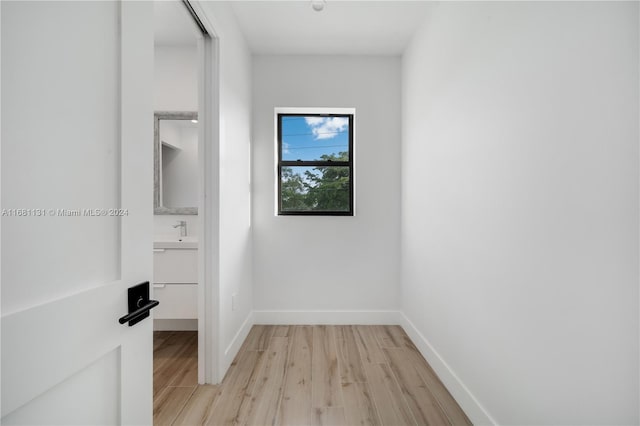 corridor with sink and light wood-type flooring