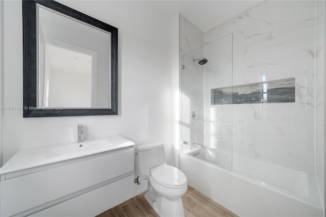 full bathroom with hardwood / wood-style flooring, tiled shower / bath combo, toilet, and vanity