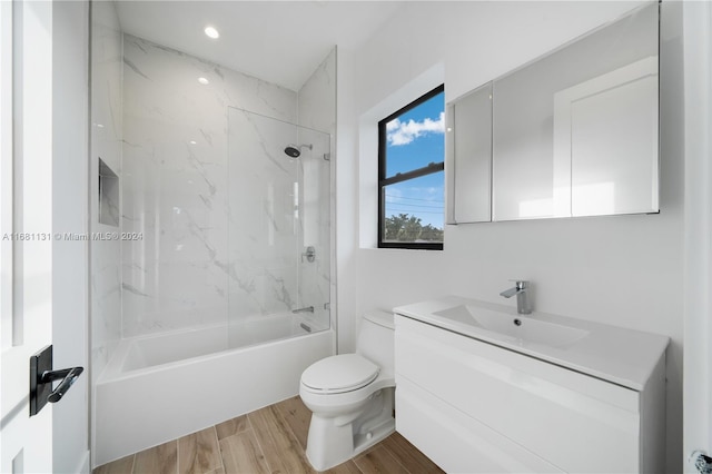 full bathroom featuring vanity, hardwood / wood-style floors, tiled shower / bath combo, and toilet