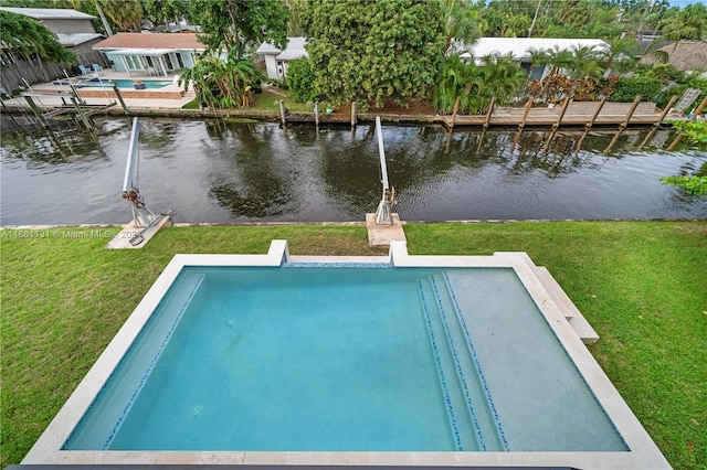 view of swimming pool featuring a yard, a water view, and a dock