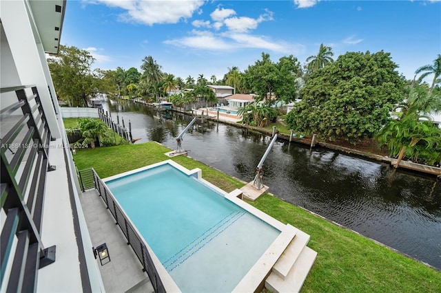 view of swimming pool with a yard, a water view, and a boat dock