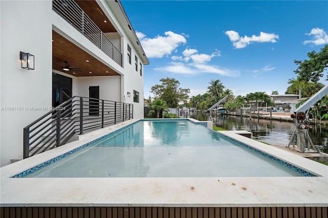 view of swimming pool with ceiling fan and a water view