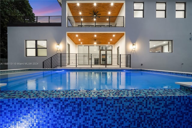 pool at dusk featuring ceiling fan