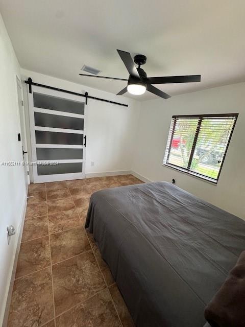 bedroom with a barn door and ceiling fan