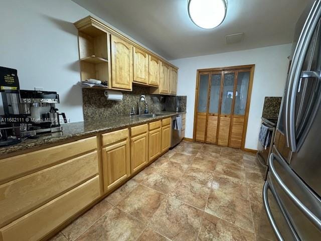 kitchen with sink, appliances with stainless steel finishes, dark stone counters, and tasteful backsplash