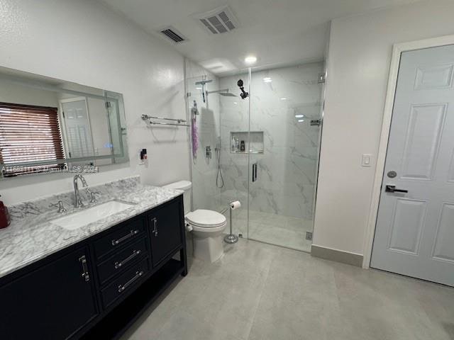 bathroom featuring vanity, toilet, and an enclosed shower