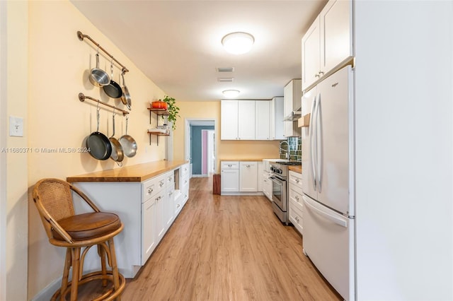 kitchen with butcher block countertops, high end stainless steel range, white cabinets, white fridge, and light hardwood / wood-style flooring