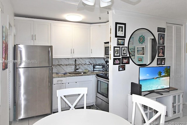 kitchen with tasteful backsplash, light stone countertops, appliances with stainless steel finishes, sink, and white cabinetry