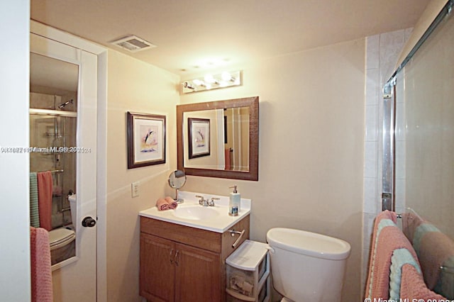 bathroom with toilet, an enclosed shower, and vanity