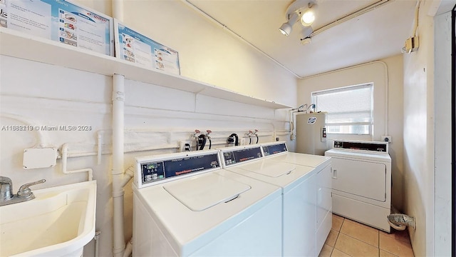 washroom featuring independent washer and dryer, sink, water heater, and light tile patterned floors