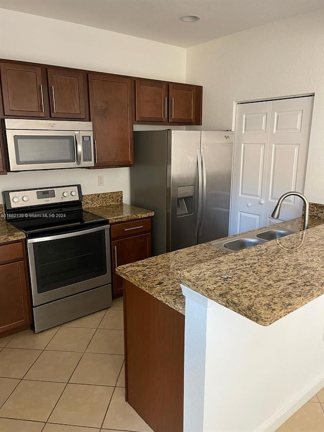 kitchen featuring light stone countertops, sink, appliances with stainless steel finishes, and light tile patterned floors