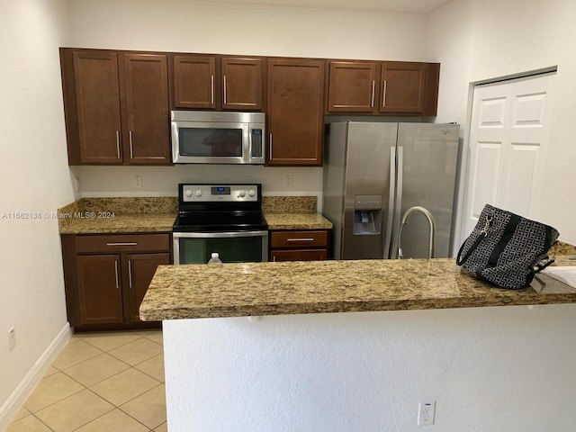 kitchen featuring light stone counters, appliances with stainless steel finishes, light tile patterned flooring, dark brown cabinetry, and sink