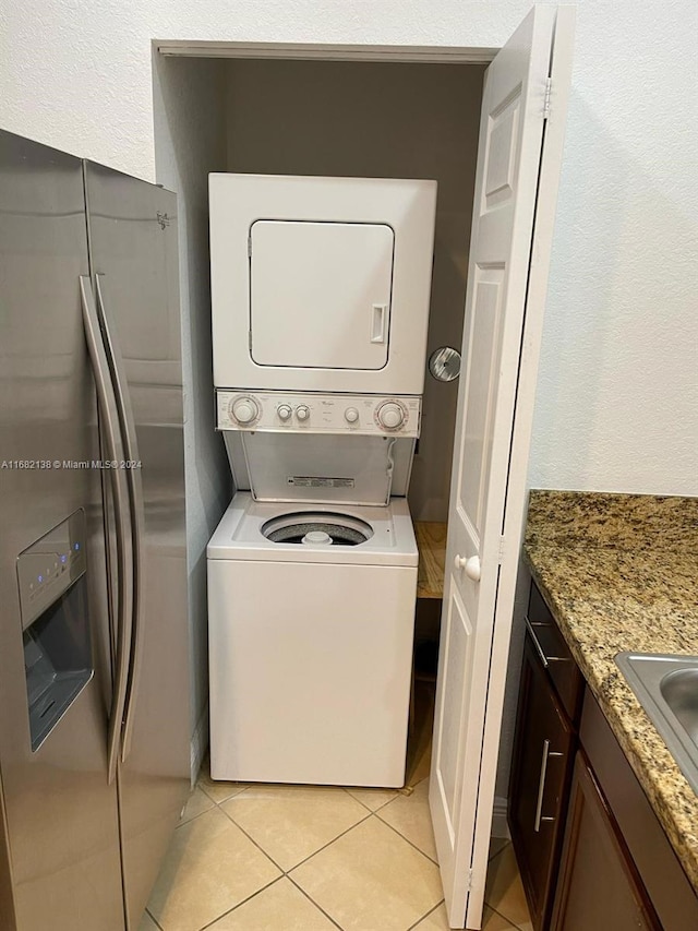 washroom with light tile patterned flooring and stacked washer and dryer