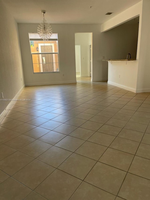 spare room featuring light tile patterned flooring and a chandelier