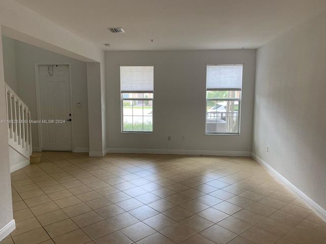 spare room with a wealth of natural light and light tile patterned flooring