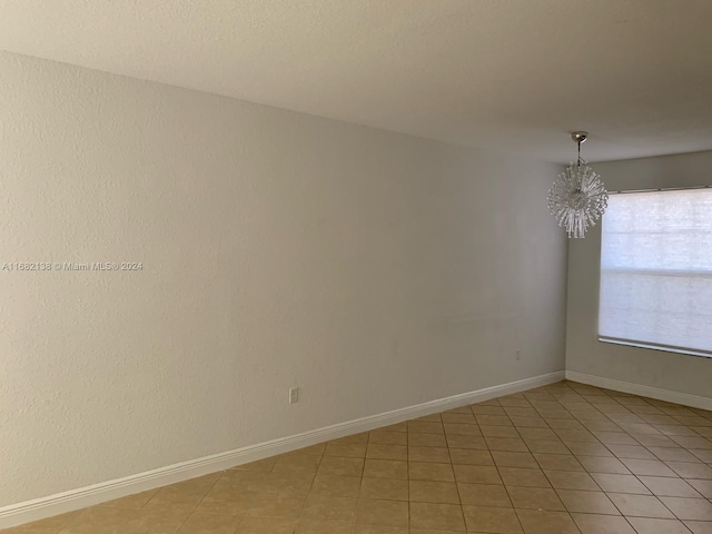 empty room with an inviting chandelier and tile patterned flooring