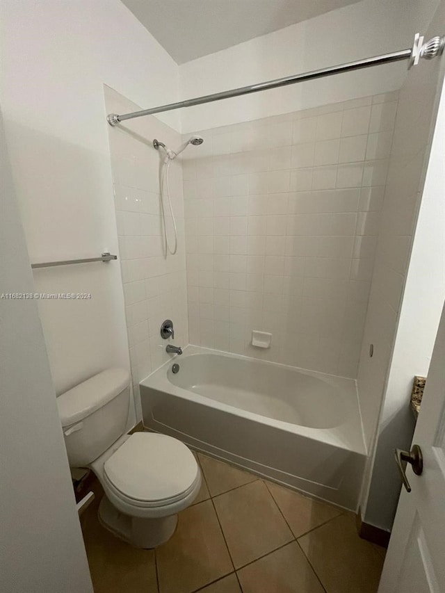 bathroom with toilet, tile patterned flooring, and tiled shower / bath