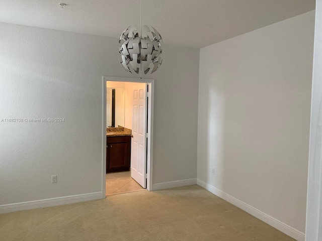 carpeted empty room featuring a notable chandelier