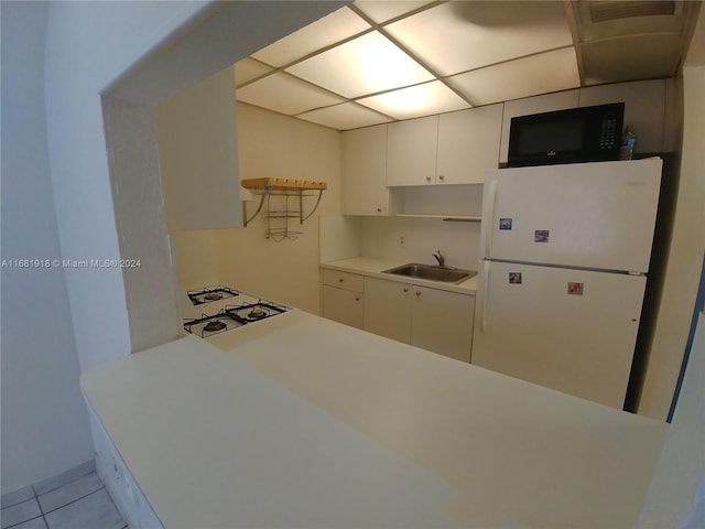 kitchen with sink, white cabinetry, white fridge, and light tile patterned floors