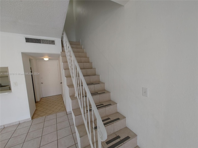 stairs with tile patterned floors and a textured ceiling