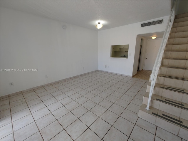 tiled spare room with a textured ceiling