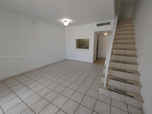 spare room with a textured ceiling and light tile patterned flooring