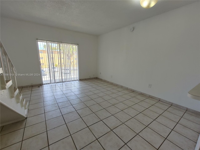 unfurnished room featuring a textured ceiling and light tile patterned floors