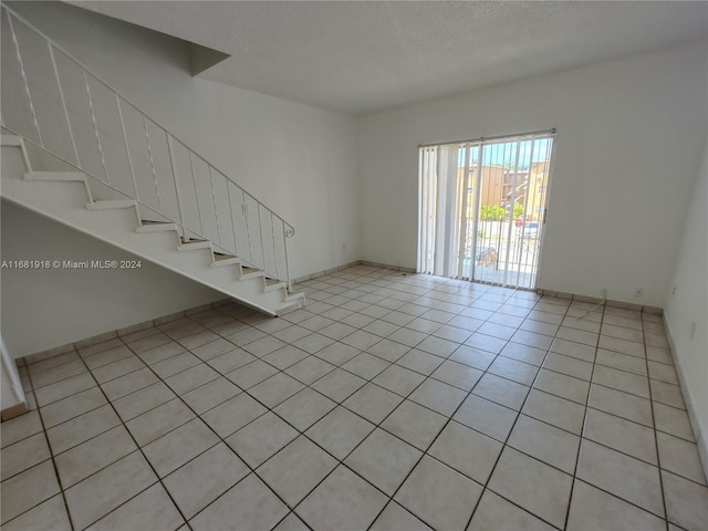1305 W 53rd St Unit 410, Hialeah, FL 33012 - unfurnished living room featuring light tile patterned floors, stairway, and a textured ceiling