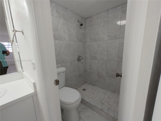 bathroom with vanity, toilet, and a tile shower