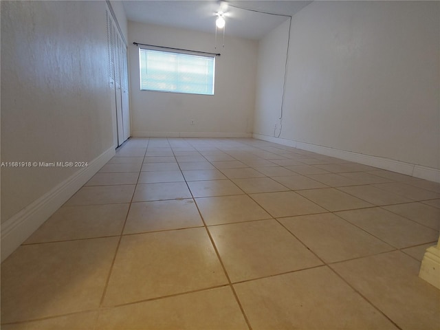 empty room with ceiling fan and light tile patterned floors