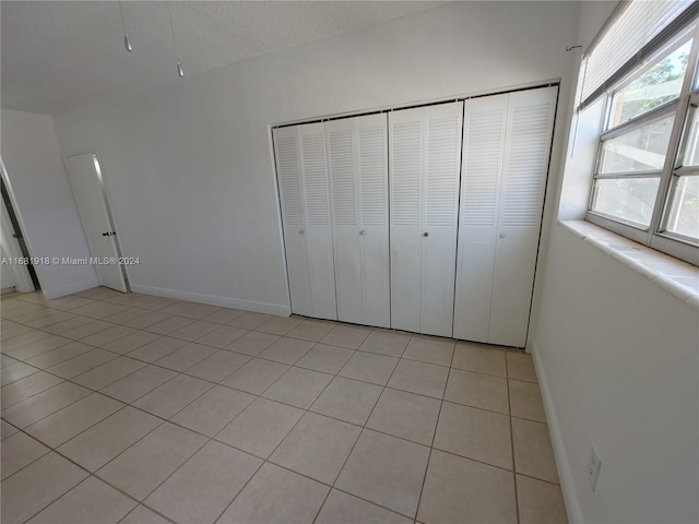 unfurnished bedroom with light tile patterned flooring, a textured ceiling, and a closet