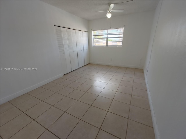 unfurnished bedroom with a closet, ceiling fan, and light tile patterned floors