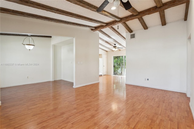 spare room featuring vaulted ceiling with beams, light wood-type flooring, and ceiling fan